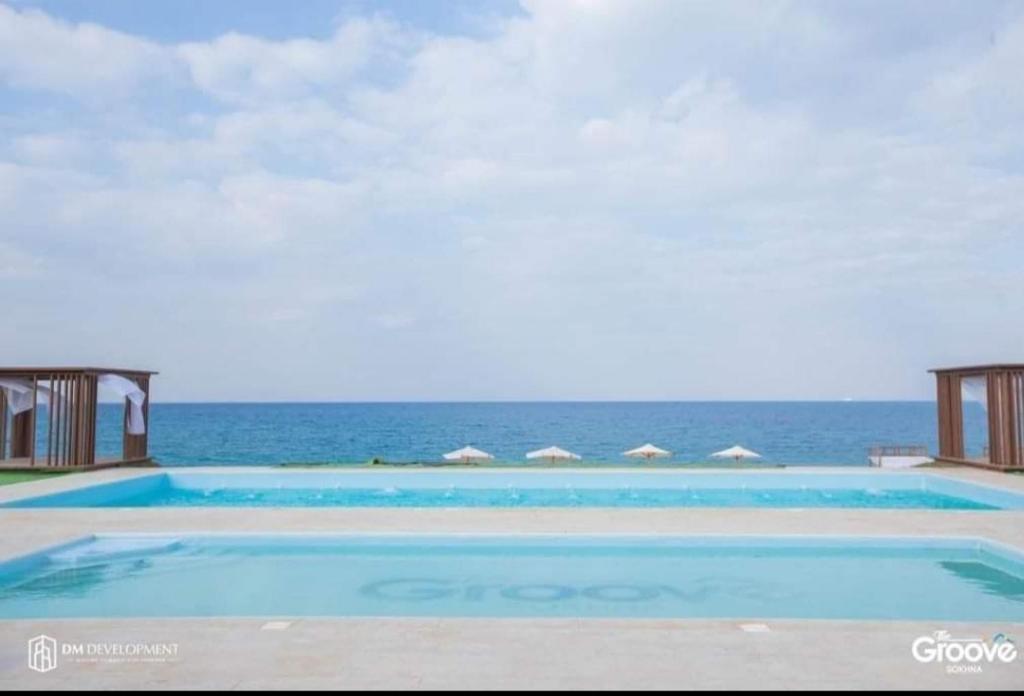 a large swimming pool with the ocean in the background at The Groove Ain Sokhna in Ain Sokhna