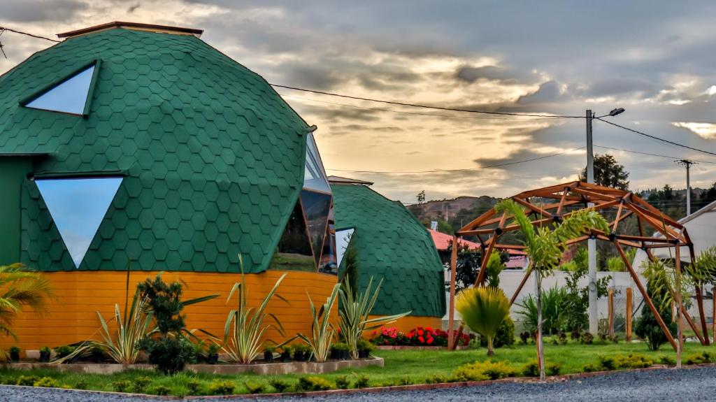 een huis met een groen dak met een letter k erop bij Magia Verde Glamping in Tinjacá