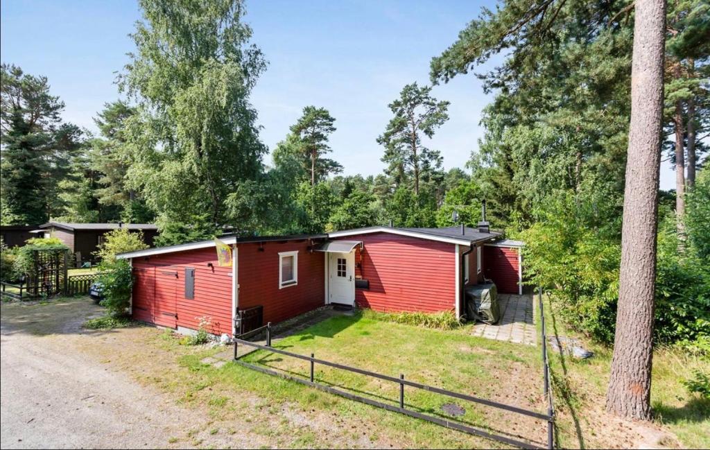 una cabaña roja en el bosque con un árbol en Stuga Sövde en Sövde