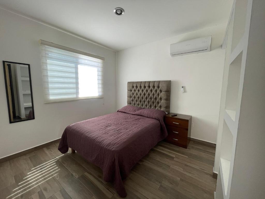1 dormitorio con cama con colcha púrpura y ventana en Depto. totalmente nuevo y amueblado, en Mazatlán