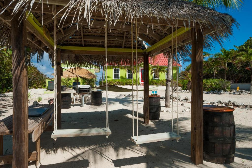 a beach with a hut with swings and a barrel at Parrot-ise 4 Bedroom Villa in Brinkleys