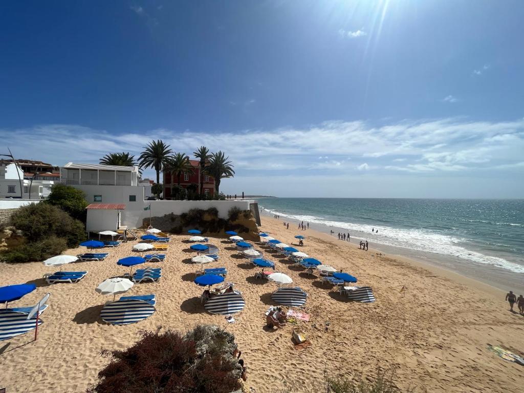 een strand met blauwe en witte parasols en de oceaan bij Sunset in Armação de Pêra