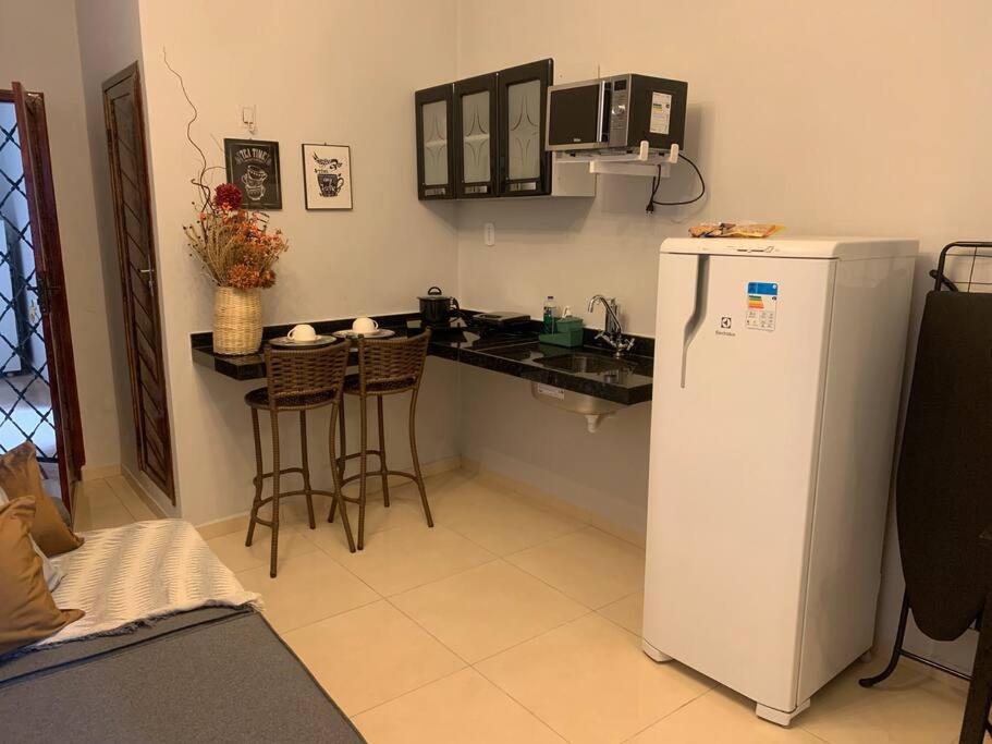 a kitchen with a counter and a white refrigerator at Studio Lindo no coração de Picos in Picos