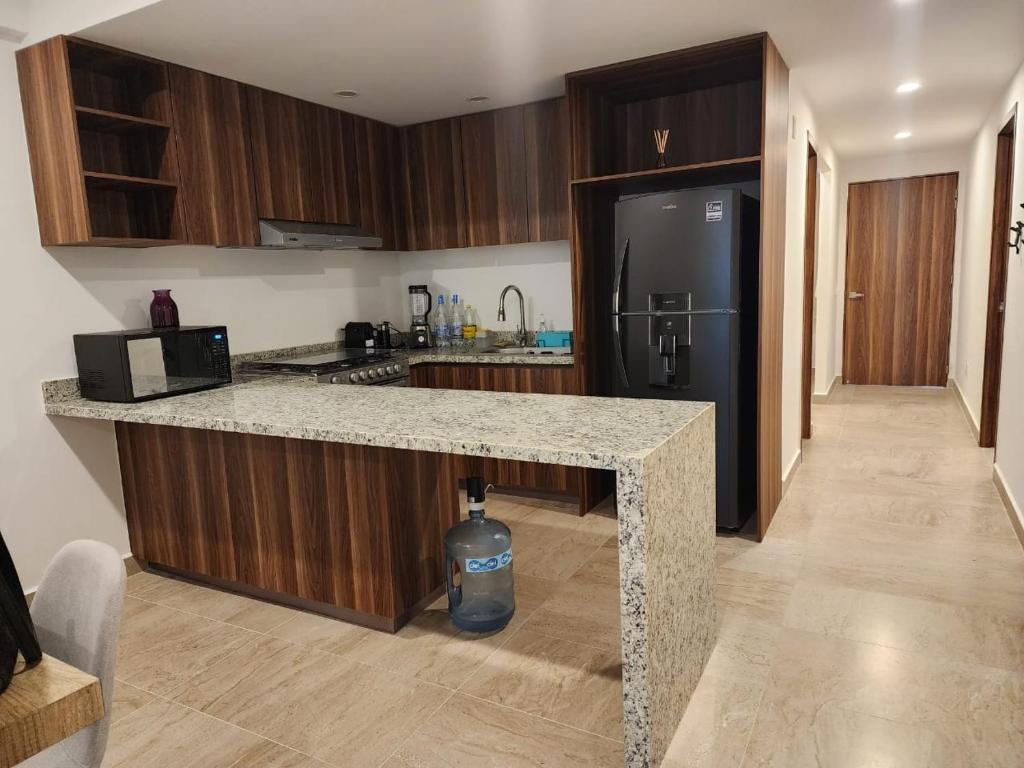 a kitchen with a granite counter top and a refrigerator at Hermoso y nuevo departamento en Nuevo Vallarta in Jarretadera