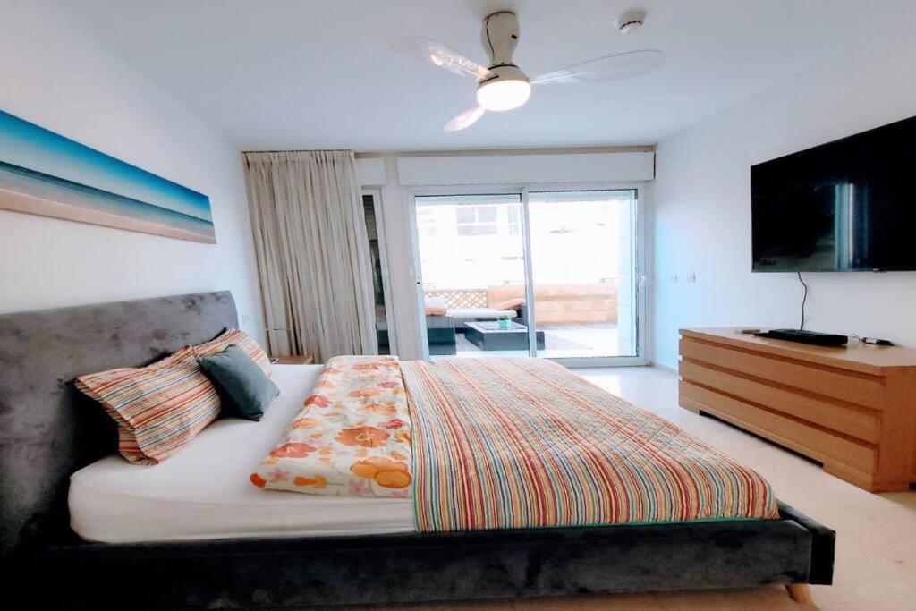 a bedroom with a bed and a dresser and a television at Feeling Home Garden Apartment in Herzliya