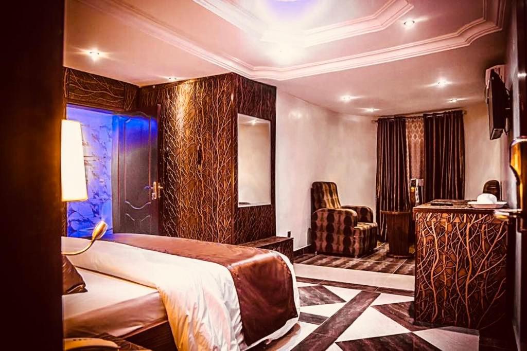 um quarto de hotel com uma cama e uma cadeira em E-Suites Hotel, Abuja em Abuja