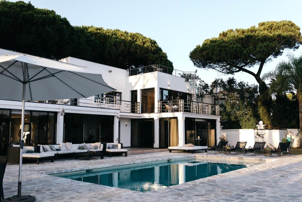 a house with a swimming pool and an umbrella at Villa GAULTHIER in Marbella