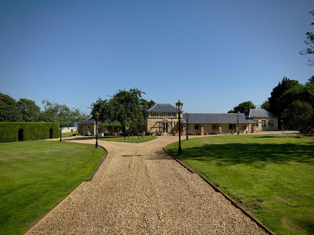 eine Kieseinfahrt, die zu einem großen Haus führt in der Unterkunft Normanton Park House - Luxury Rutland Water Home in Oakham