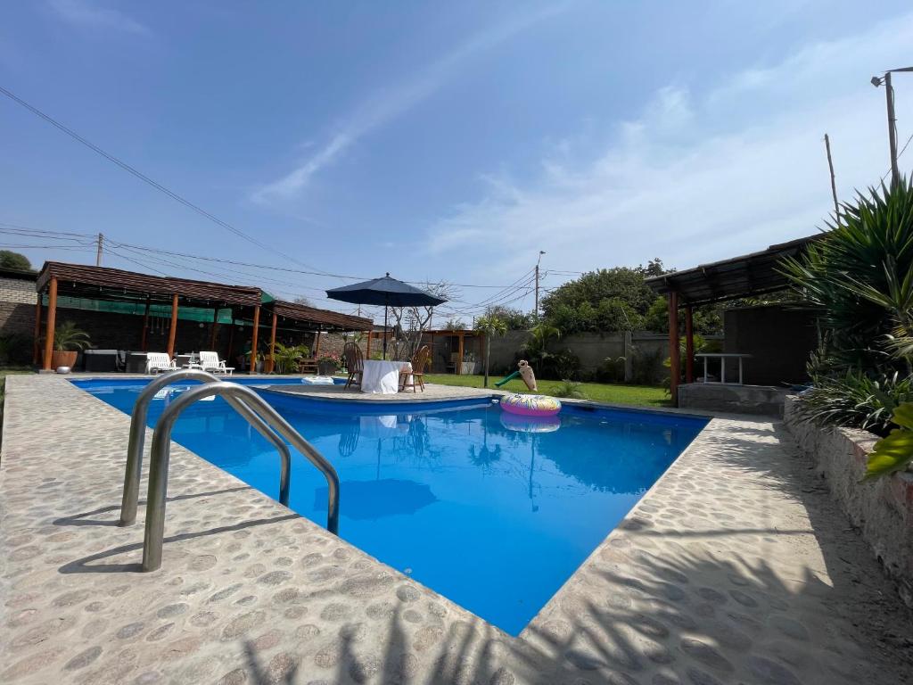 een zwembad met blauw water en een parasol bij Casa en San Fernando Pachacamac in Lima