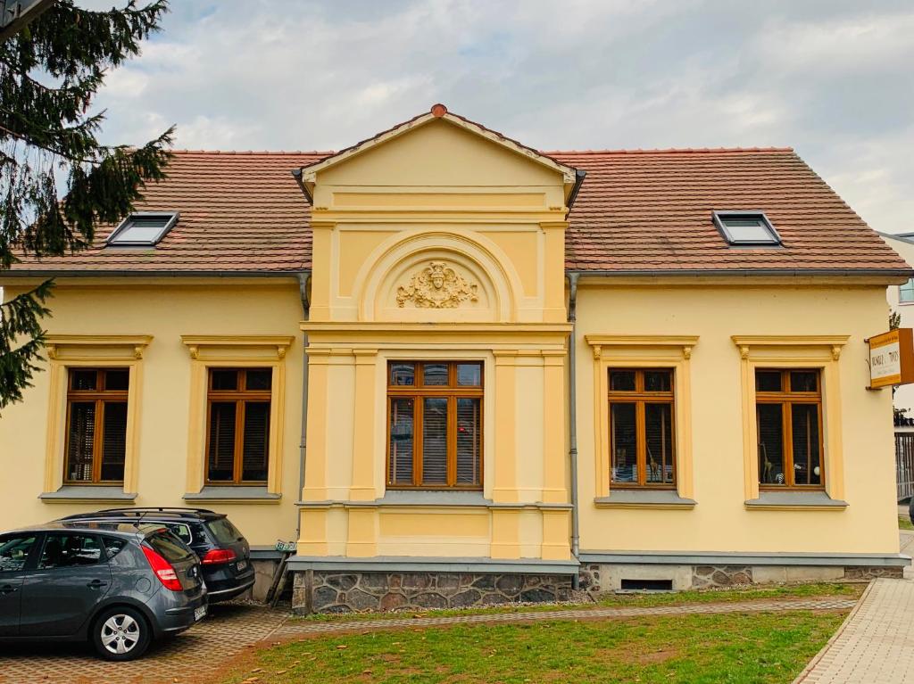 una casa gialla con una macchina parcheggiata di fronte di Stilvolle Ferienwohnung in historischer Stadtvilla a Neubrandenburg