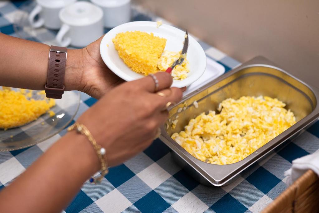 a person eating food in a pan on a table at POUSADA REAL DAS FLORES in Porto Velho