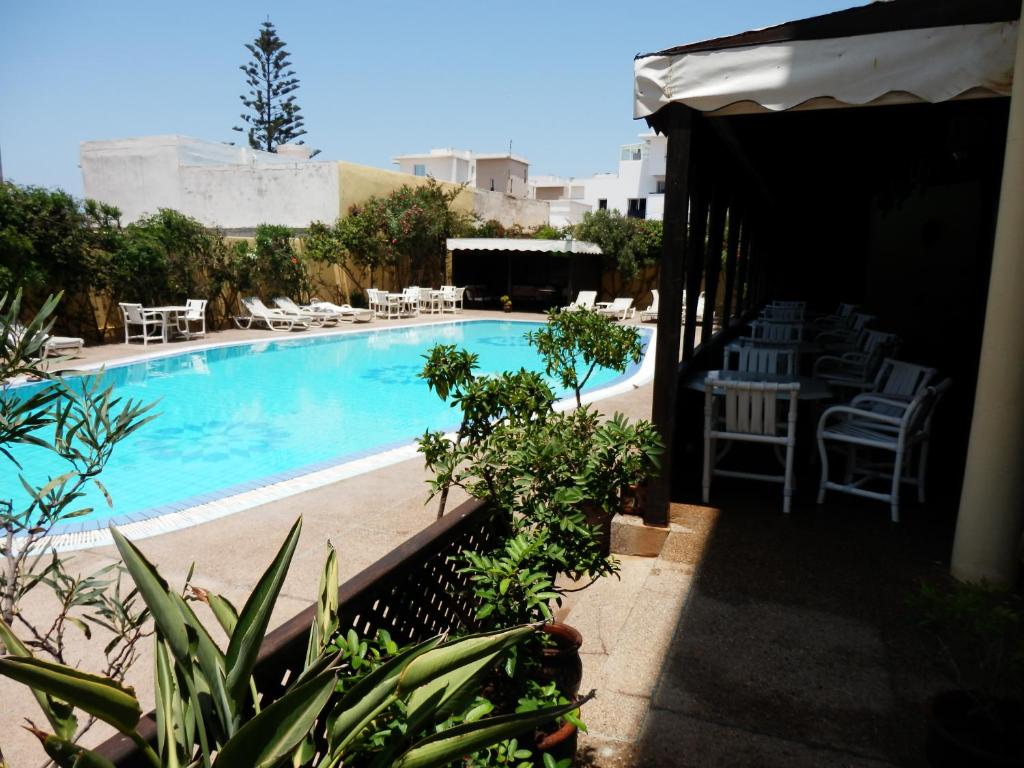 a swimming pool with chairs and a table and chairs at Riad Zahra in Essaouira