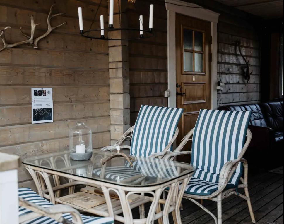 2 Stühle und ein Glastisch auf einer Terrasse in der Unterkunft Mellanströms Stugby in Arjeplog