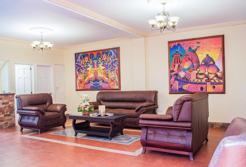 ein Wohnzimmer mit Stühlen, einem Tisch und einem Gemälde in der Unterkunft Luna de Plata in Quetzaltenango