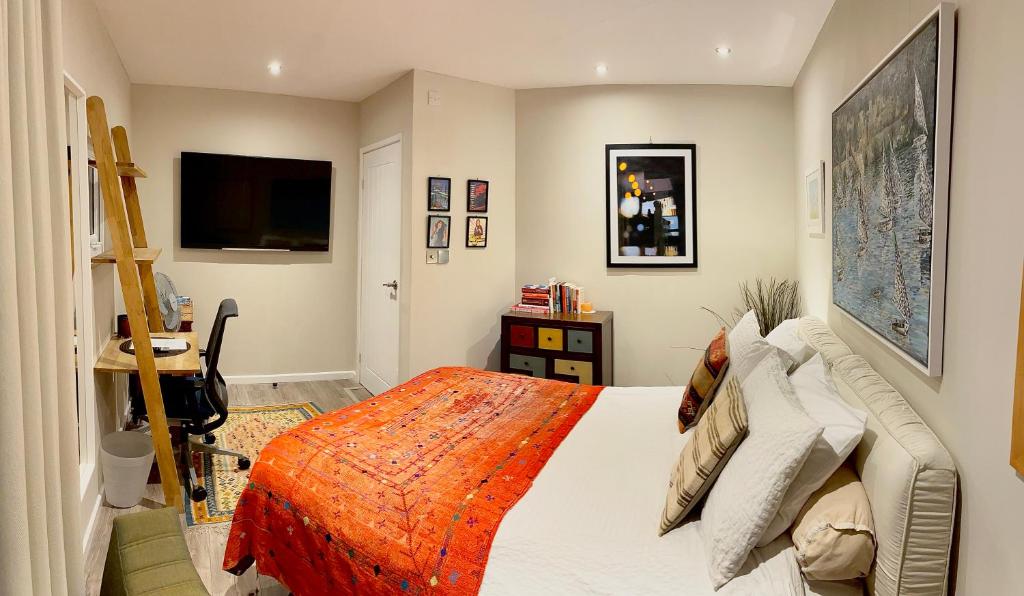 ein Schlafzimmer mit einem Bett mit einer orangefarbenen Decke in der Unterkunft Modern, Gr Floor 1 bed, bathroom, garden & private entry. in Cambridge