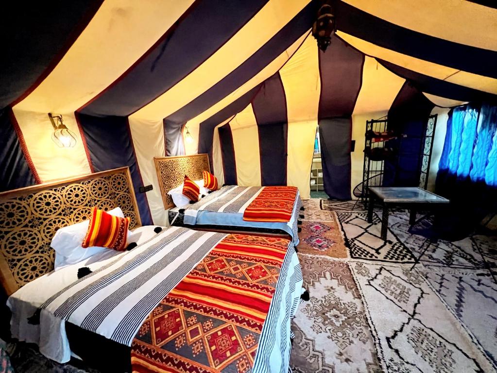 een slaapkamer met 2 bedden in een tent bij Dream luxury camp in Merzouga