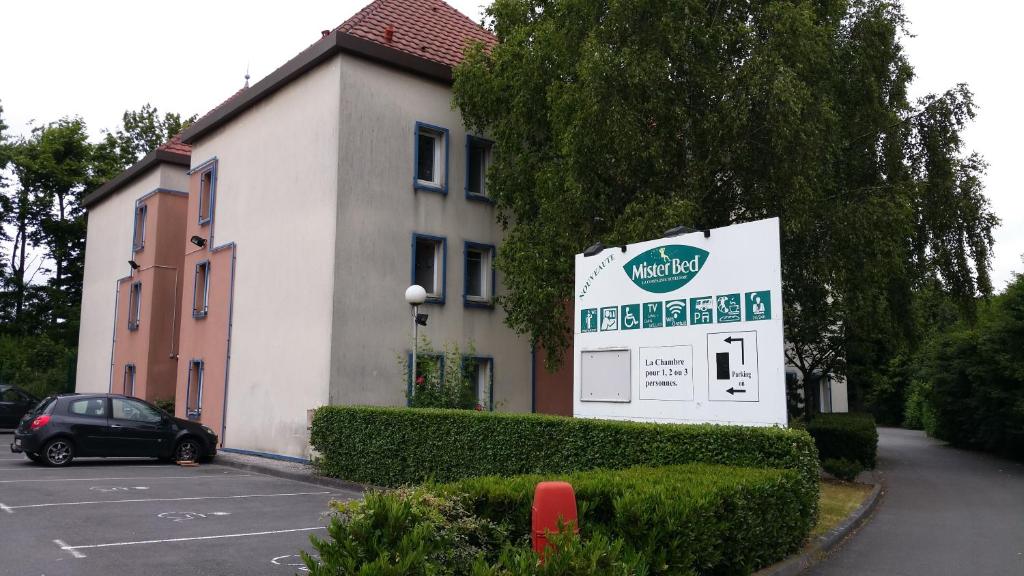 un bâtiment avec un panneau en face d'un parking dans l'établissement Mister Bed Lomme, à Lomme