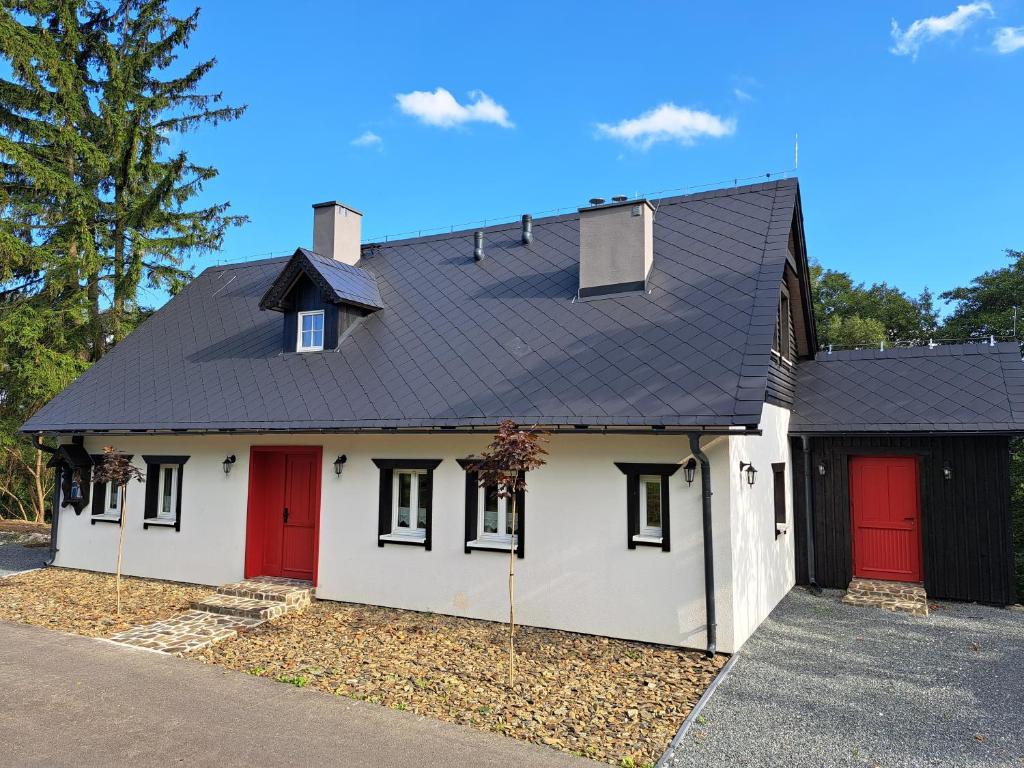 a white house with red doors and a black roof at Czerwone Drzwi in Stronie Śląskie