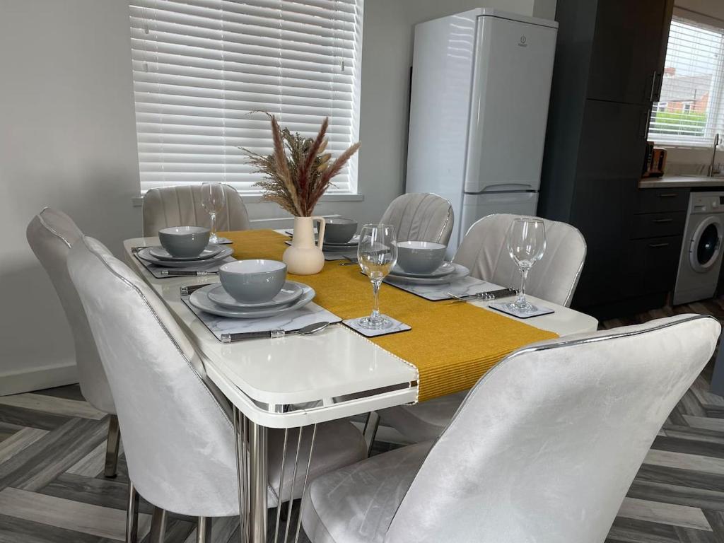a dining room table with white chairs and a yellow table cloth at Redcar Retreat in Redcar