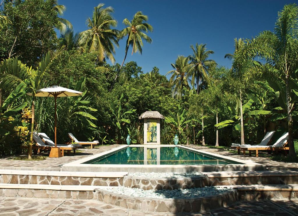 a swimming pool with a gazebo and palm trees at Cili Emas Oceanside Resort in Tejakula