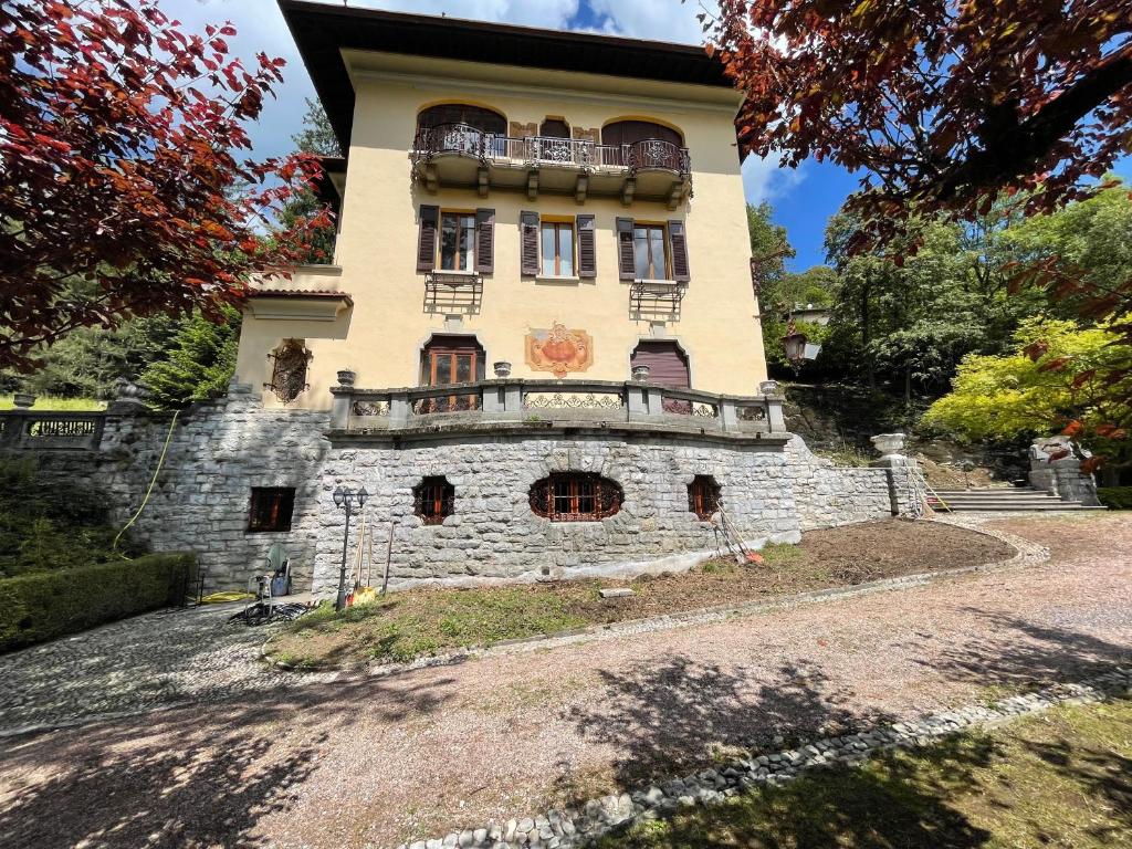 un gran edificio de piedra con balcón en la parte superior. en Villa Volpe Como, en Lanzo d'Intelvi