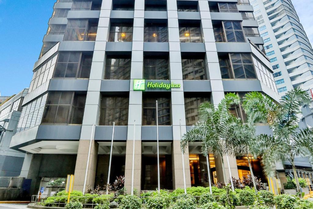 ein hohes Gebäude mit einem Schild davor in der Unterkunft Holiday Inn Manila Galleria, an IHG Hotel in Manila