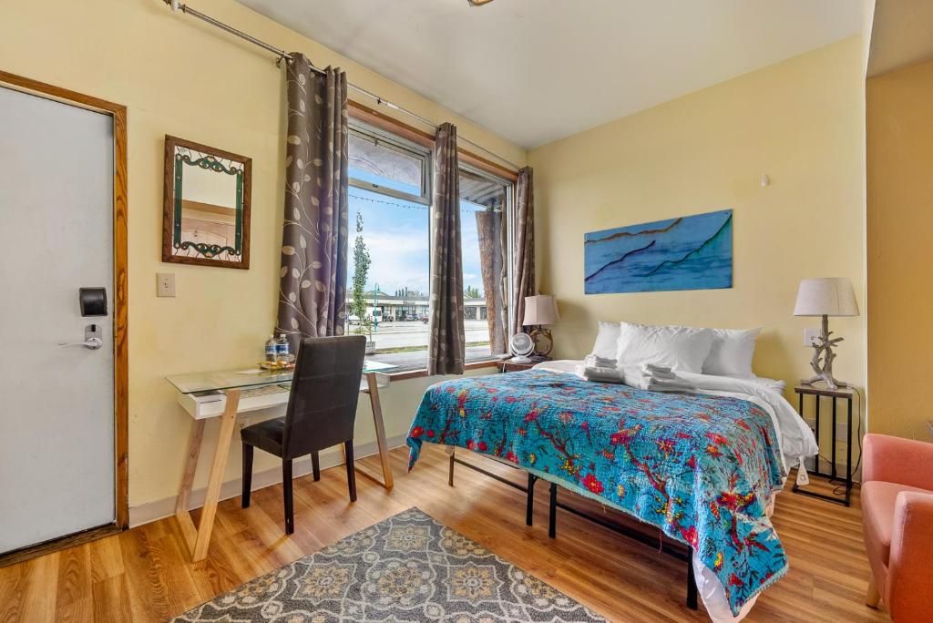 安克拉治的住宿－曲普奎嘉琪旅館，一间卧室配有一张床、一张书桌和一个窗户。