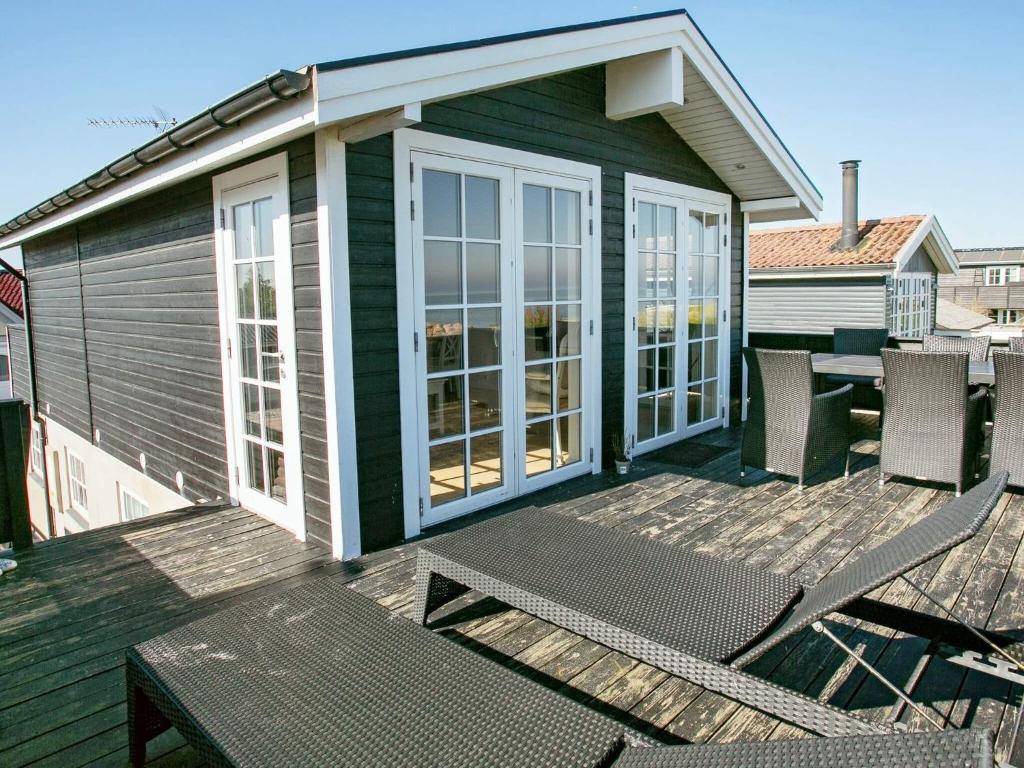 een groen huis met een terras met stoelen erop bij Two-Bedroom Holiday home in Otterup 12 in Otterup