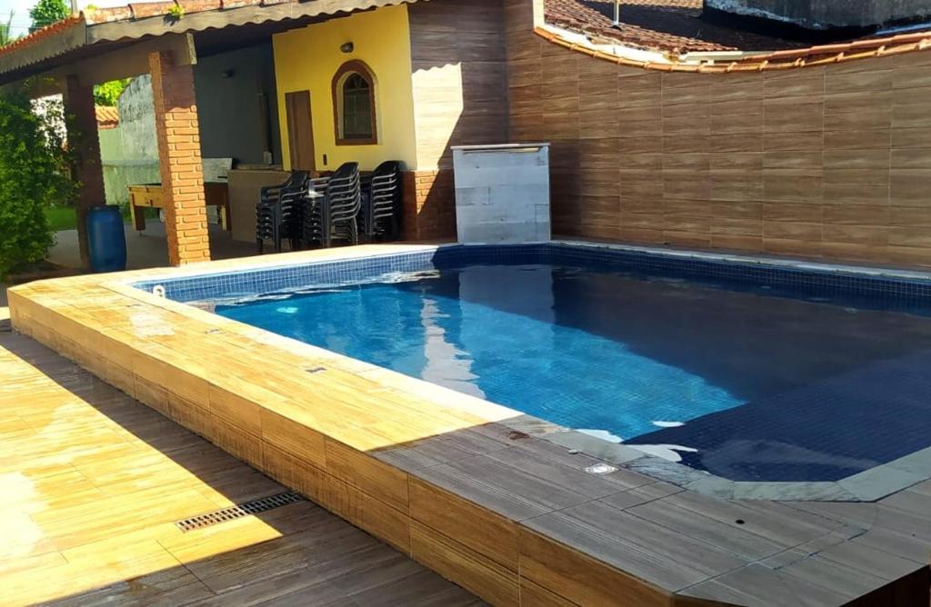 a swimming pool with a wooden deck and a house at Casa na Praia de Bertioga in Bertioga