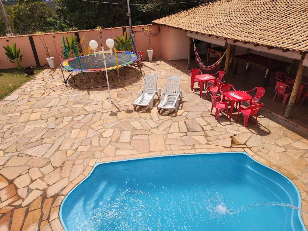 um quintal com uma piscina, cadeiras e uma mesa em Chalés Recanto dos Pássaros em São Tomé das Letras