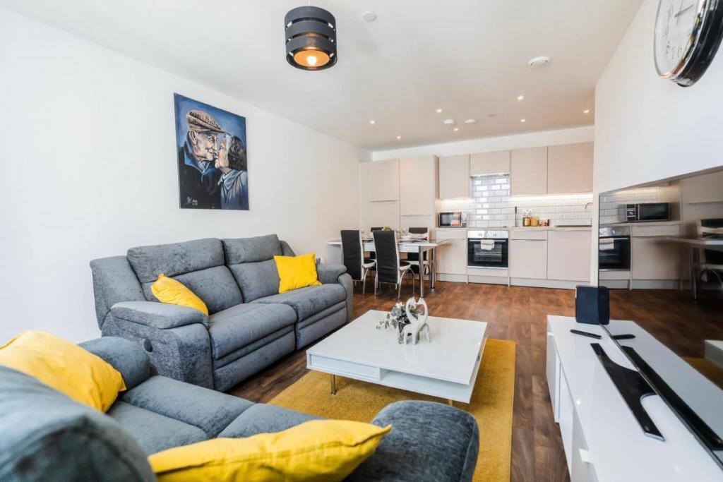 a living room with a blue couch and yellow pillows at Contemporary 2 bedroom Apartment - Birmingham City Centre - Digbeth Bullring in Birmingham