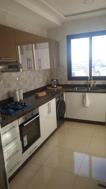 a kitchen with white cabinets and a large window at A loué appartement in Agadir