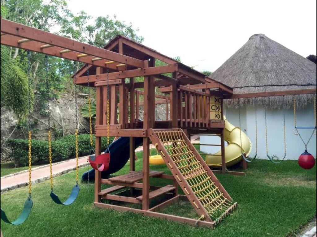 a play house with a swing and a playground at Cozy Apartments in Puerto Morelos in Puerto Morelos