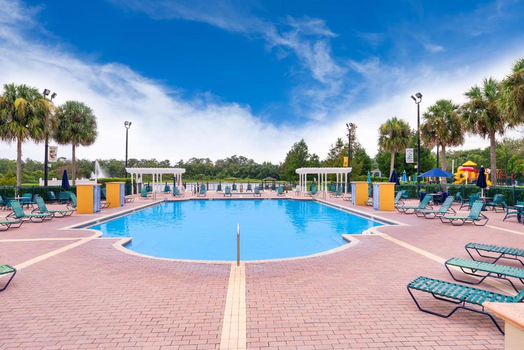 una gran piscina con sillas y un parque infantil. en Enchanted Townhome near Disney Parks 3Br, en Kissimmee