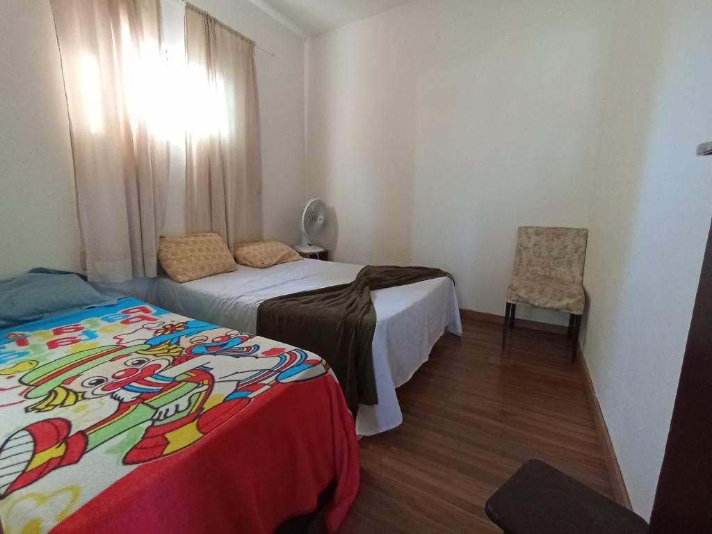 a small bedroom with two beds and a chair at Casa pertinho da praia com piscina, wifi; in Vila Velha