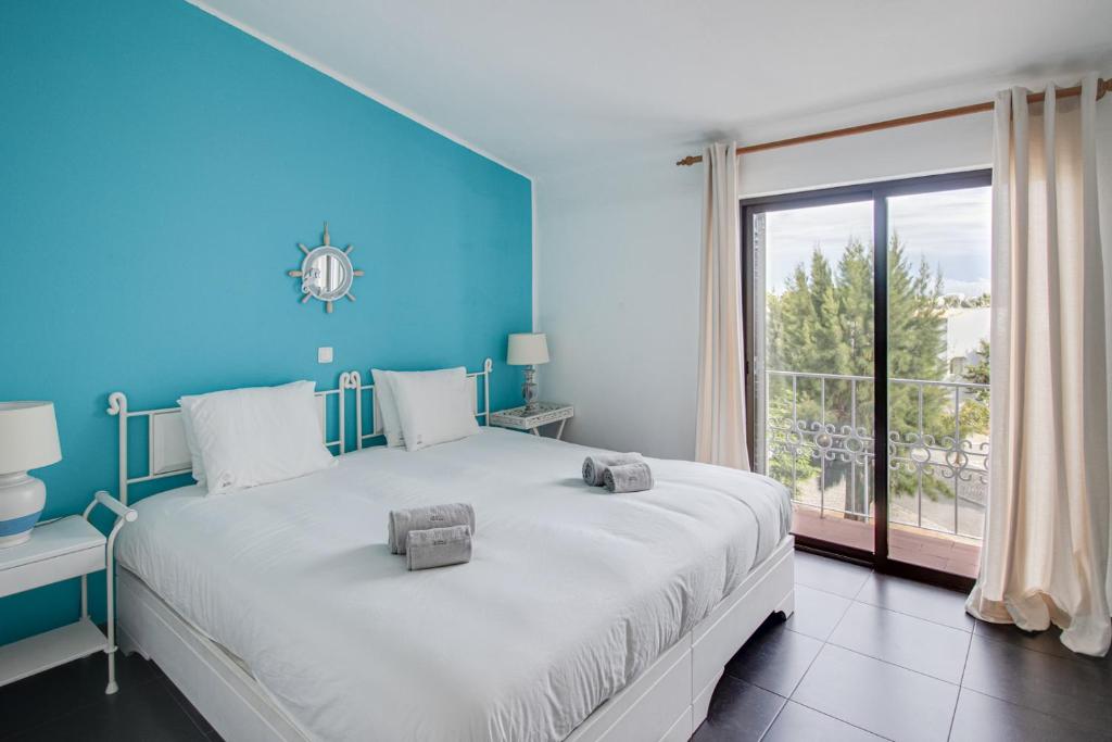 een blauwe slaapkamer met een groot bed en een raam bij Seaside Retreat with Pool, AC, and Fast Wi-Fi in Albufeira