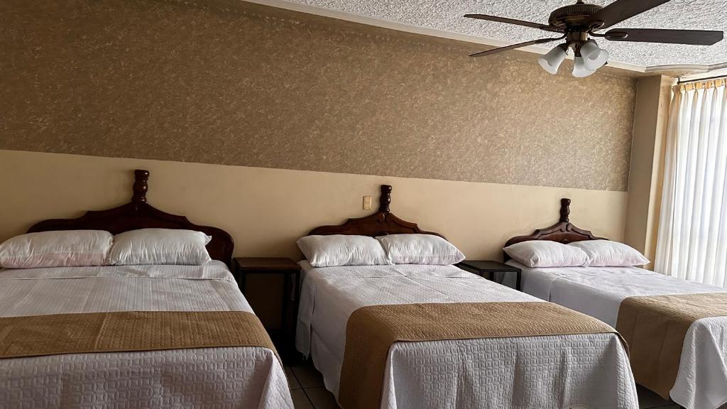 a room with two beds and a ceiling fan at Hotel Palacio in San Juan de los Lagos