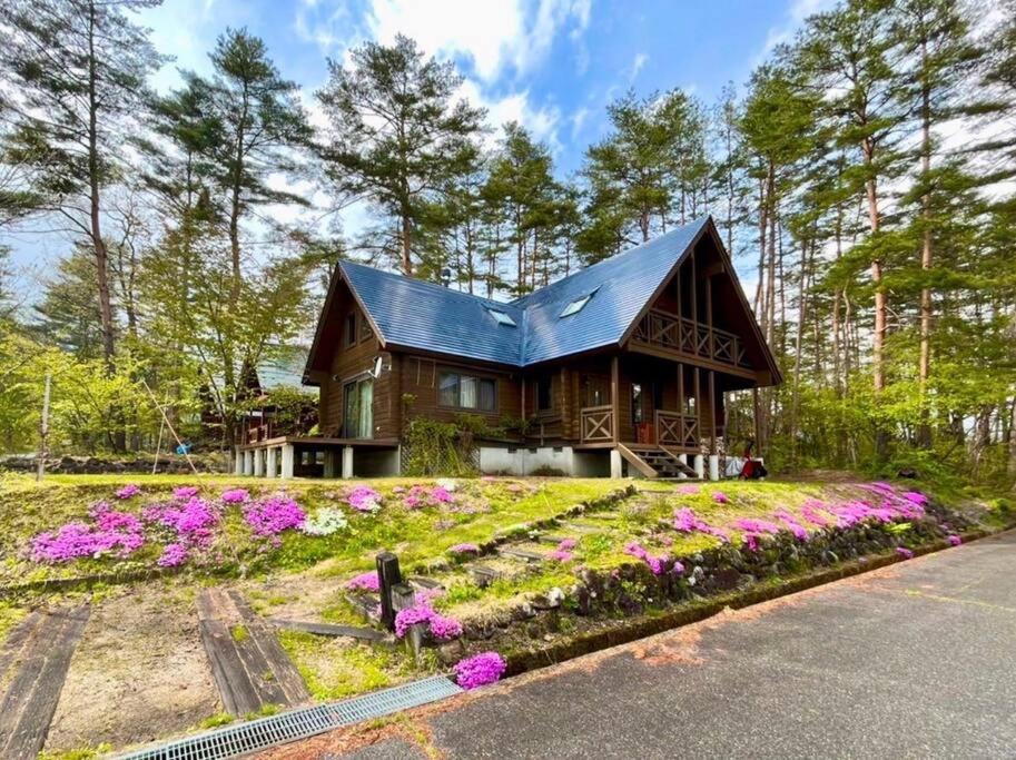 uma casa com um telhado preto e algumas flores em 白馬のスキー場まで４分お洒落なログハウス『白馬 MAMMOTH HOUSE』 em Hakuba