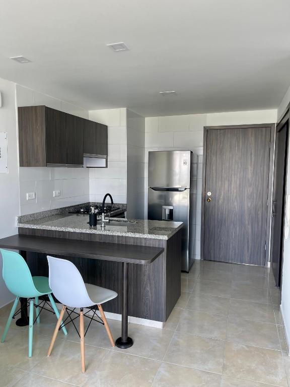 a kitchen with a counter and chairs and a refrigerator at Santorini Elite in Pereira