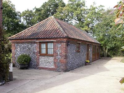 a small brick building with a window in a driveway at Orchard Cottage-23895 in Aylmerton