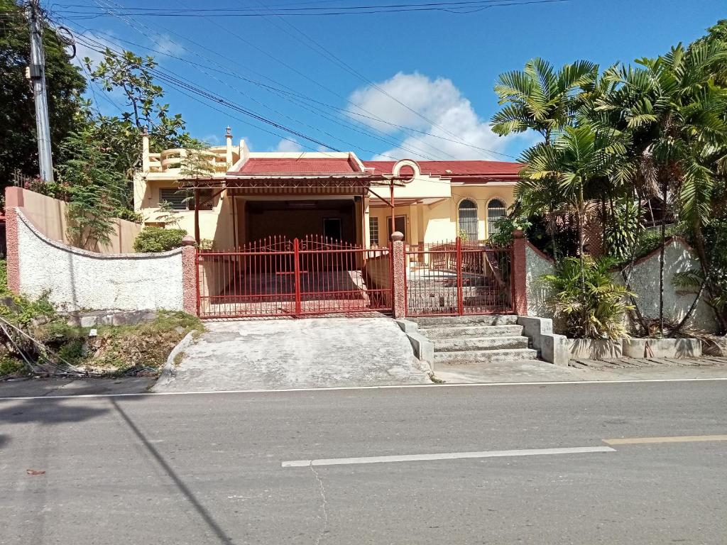 ein Haus mit einem roten Tor auf einer Straße in der Unterkunft Larot's Vacation House - Rooms Only in Siquijor