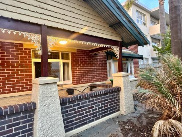 a brick house with a retaining wall in front of it at Glenelg House in Adelaide