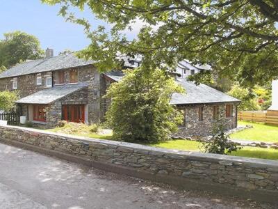 a stone house with a stone wall next to a street at Helm View in Windermere
