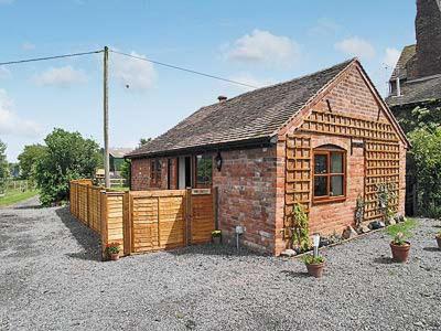 a small brick house sitting on top of a gravel yard at The Bothy in Malvern Wells