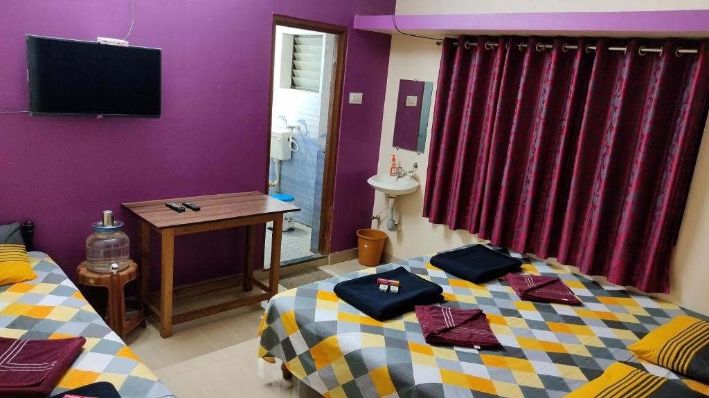 a room with two beds and a table and a tv at DANDELI CROCODILE EDGE HOME STAY in Dandeli