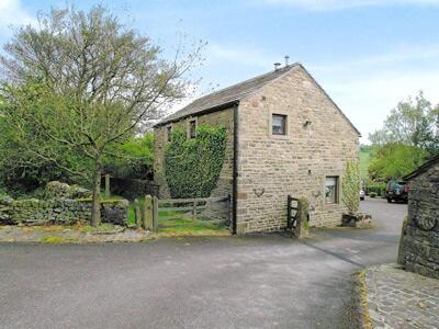 un antiguo edificio de piedra con una puerta y una valla en Owl Cotes Cottage en Cowling