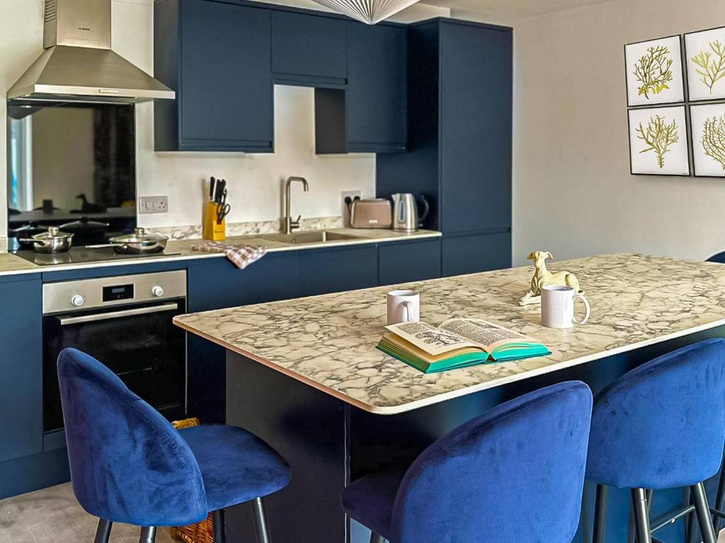 Apartment 7-uk42738 في وايتستابل: مطبخ مع دواليب زرقاء وكاونتر مع كراسي زرقاء