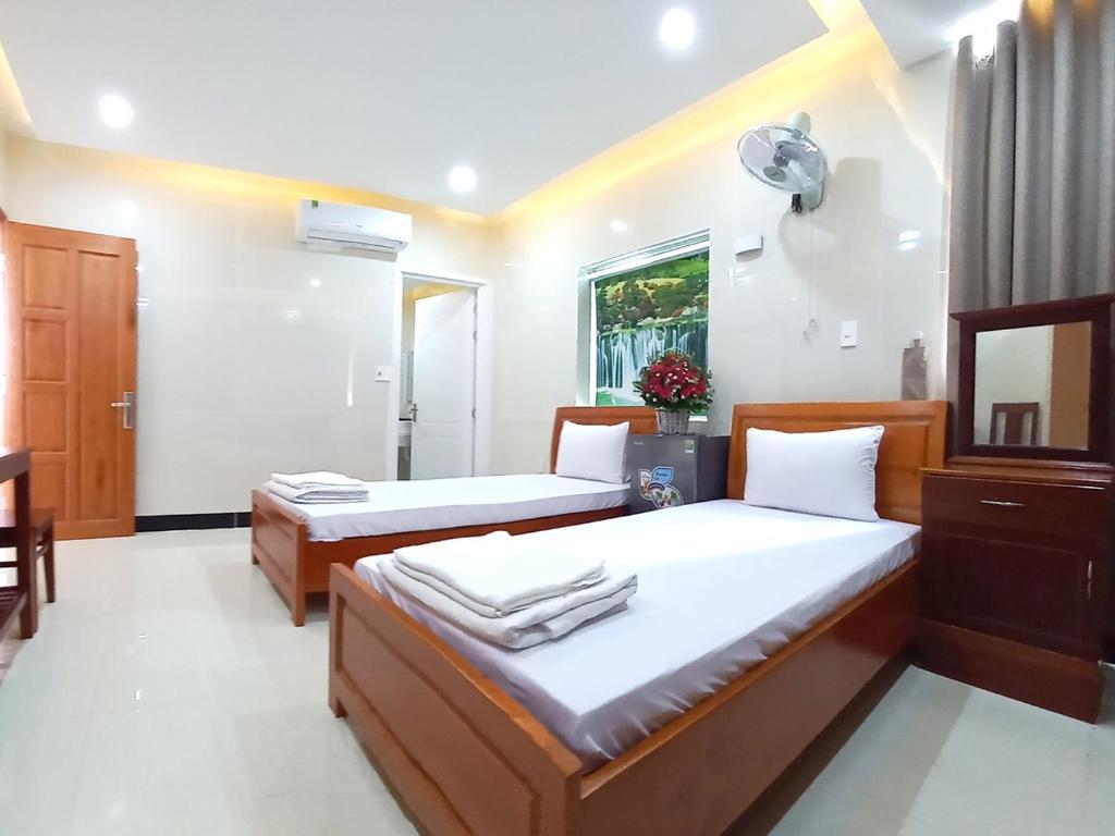 a bedroom with two beds and a mirror at KHÁCH SẠN CÚC PHƯƠNG (CÚC PHƯƠNG HOTEL) in Dĩ An
