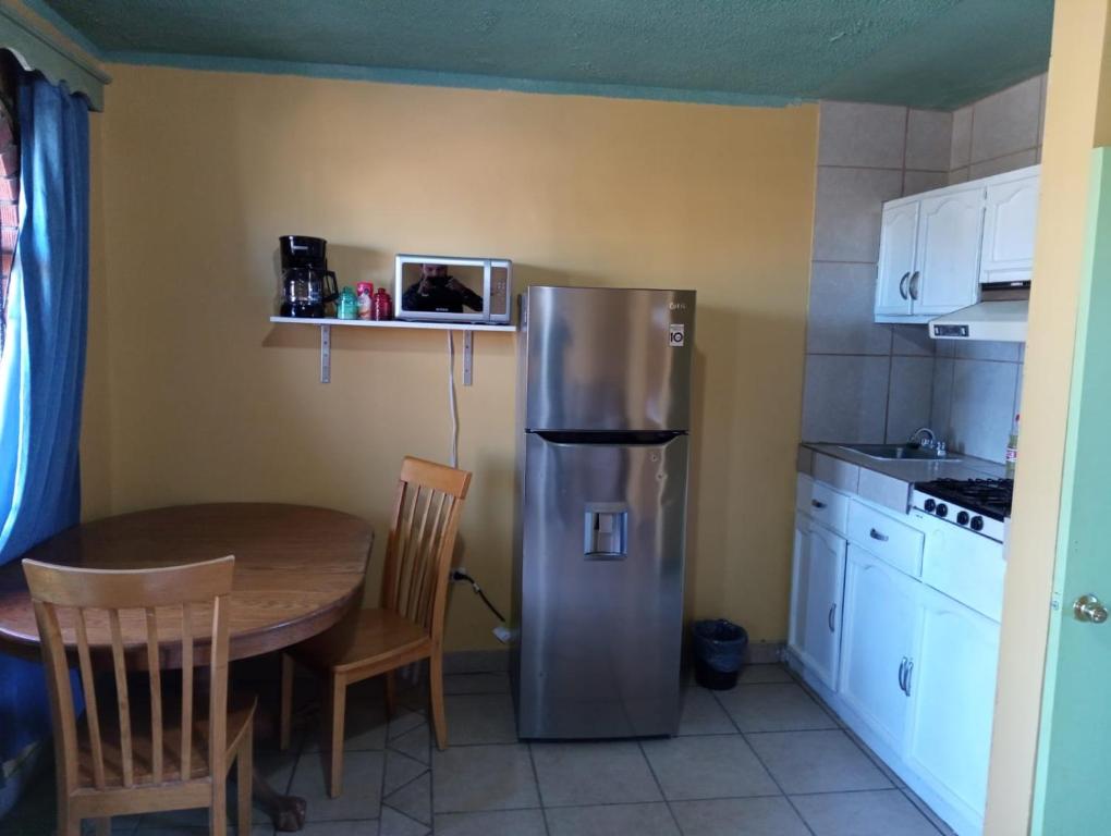 a kitchen with a table and a stainless steel refrigerator at Departamento #8 in San Felipe