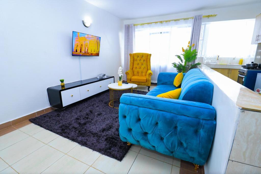 a living room with a blue couch and a kitchen at Garden estate 1 bedroom furnished apartment in Nairobi